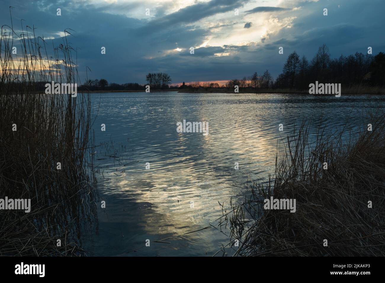 Nuages sombres le soir sur le lac et réflexion de lumière dans l'eau Banque D'Images