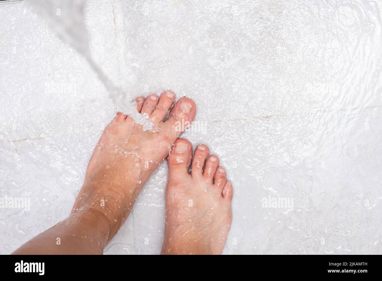 Femme se lavant les pieds, gros plan. Une femme se tient sous l'eau de la douche. Banque D'Images