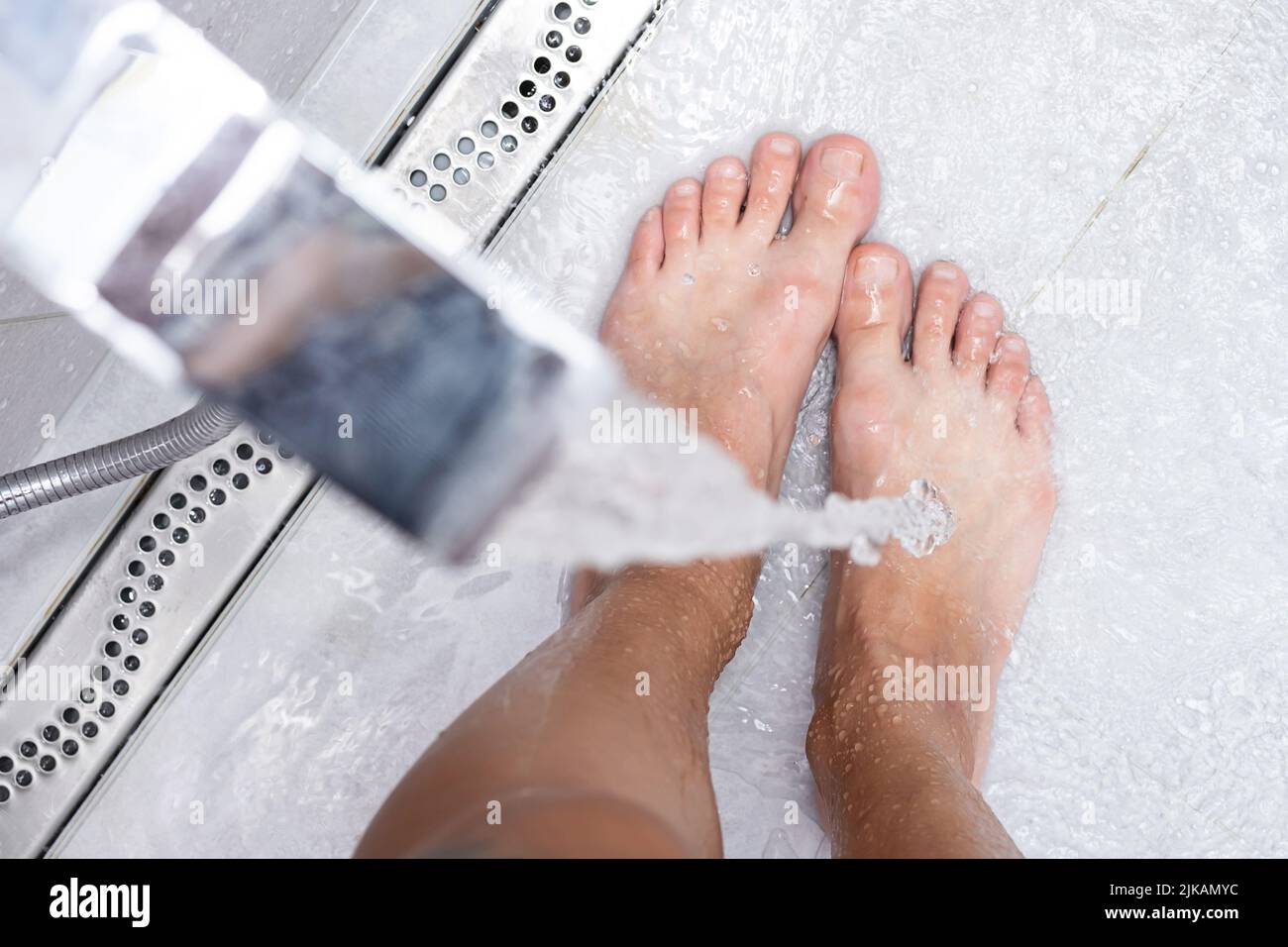 Femme se lavant les pieds, gros plan. Une femme se tient sous l'eau de la douche. Banque D'Images