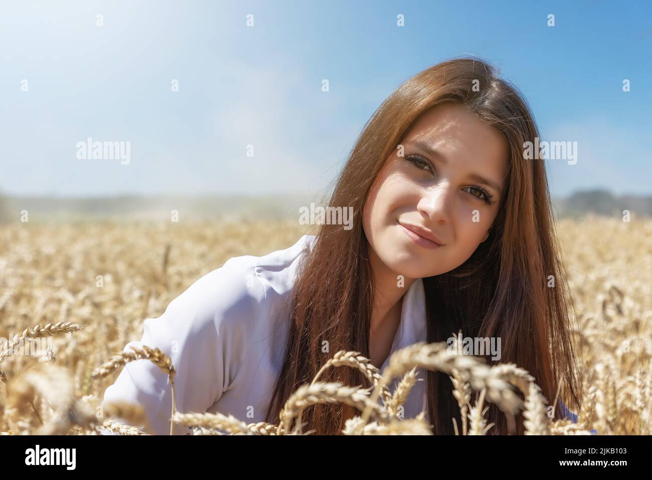 Une jeune femme brune souriante pose dans un champ de blé de plus près. Horizontalement. Banque D'Images