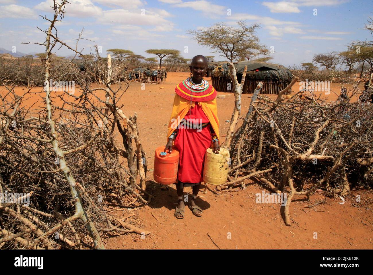 Mary Yanaiyo 47, une femme de tribus Samburu porte des jerricans à l'extérieur de sa maison de manyatta après avoir reçu de la viande de secours dans le stockage des animaux émaciés dans un programme par le gouvernement et la Croix-Rouge du Kenya pour acheter du bétail, Abatter et distribuer la viande comme aliment de secours aux familles les plus touchées à la suite d'une sécheresse prolongée près de Lengusaka à Wamba, dans le comté de Samburu, au Kenya 27 juillet 2022. REUTERS/Thomas Mukoya Banque D'Images