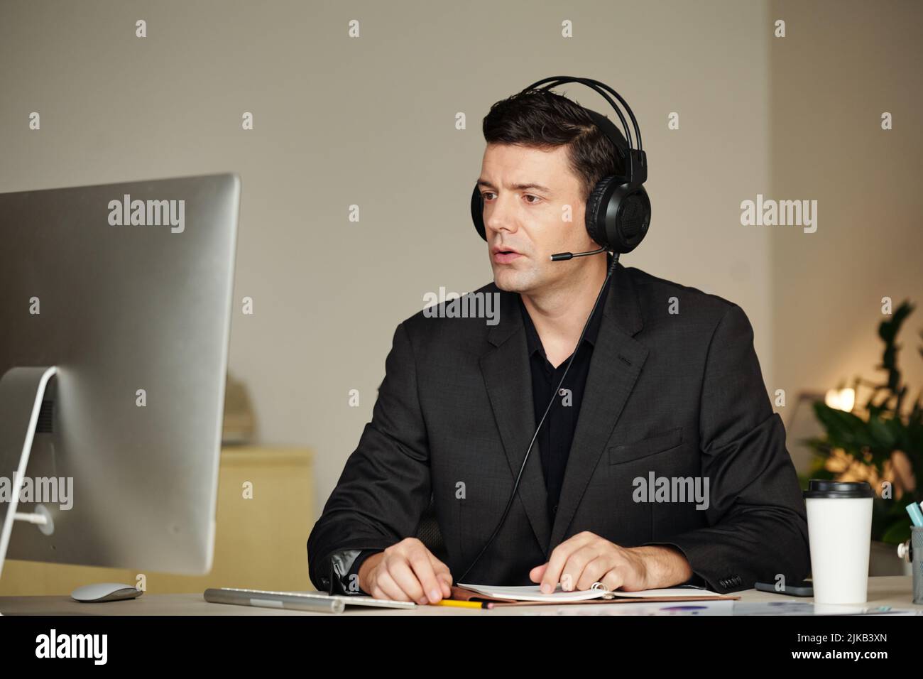 Un responsable professionnel sérieux portant un micro-casque/une oreillette  lorsqu'il répond à un appel du client ou du client Photo Stock - Alamy