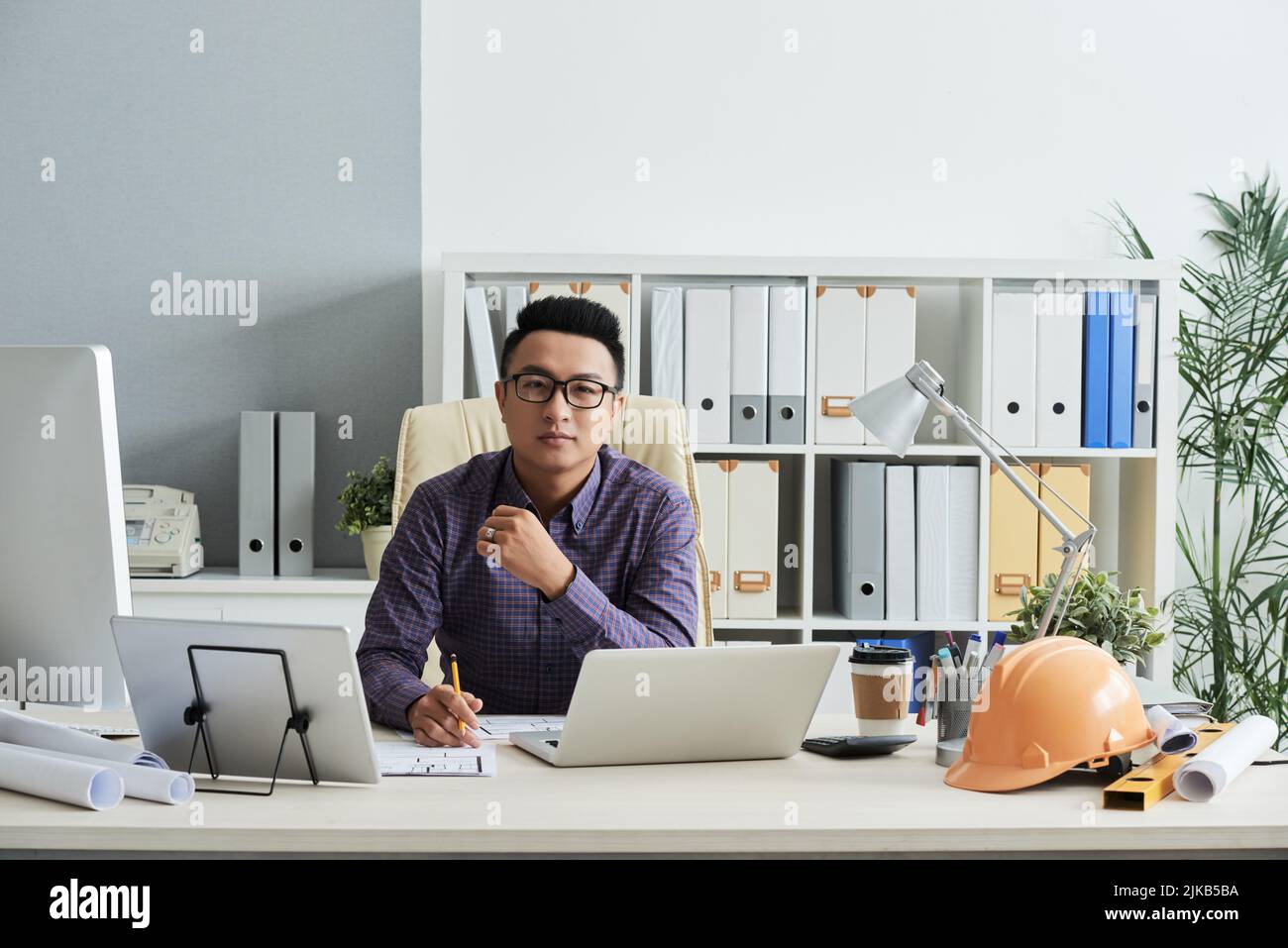 Portrait d'un jeune ingénieur souriant travaillant dans son bureau Banque D'Images