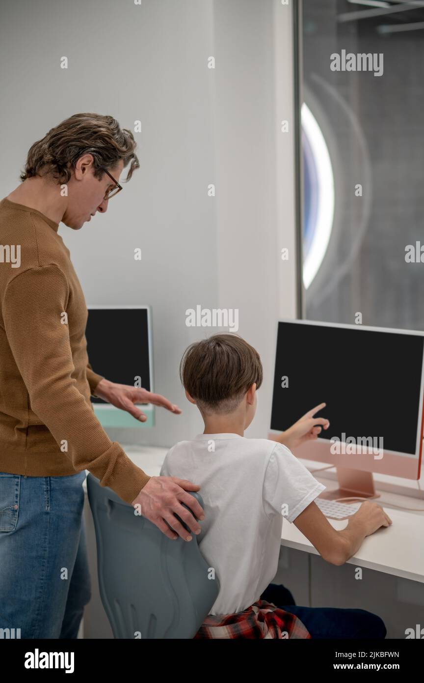 Les écoliers et leur enseignant aux ordinateurs dans une salle de classe Banque D'Images