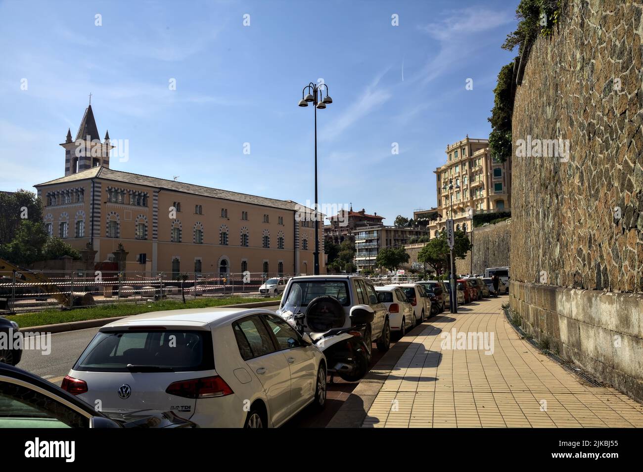 Route avec voiture garée par son bord vue d'un trottoir à côté d'un mur de pierre sur une journée ensoleillée Banque D'Images