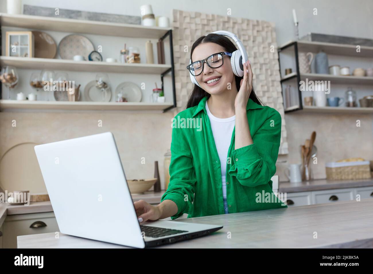 Jolie jeune femme travaillant avec un ordinateur portable et d'écouter la musique à la maison Banque D'Images