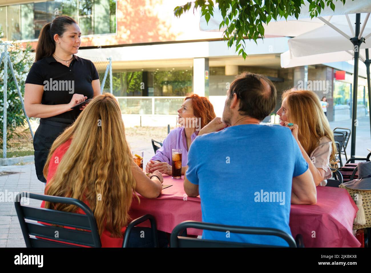 Serveuse prenant une commande pour un groupe d'amis matures dans un restaurant. Banque D'Images