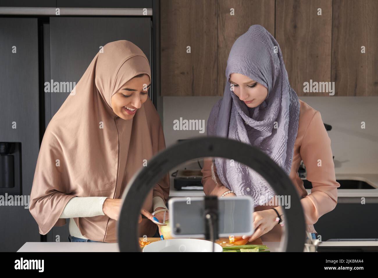 Deux bûcherons musulmans parlant tout en faisant une vidéo de cuisine dans la cuisine. Banque D'Images