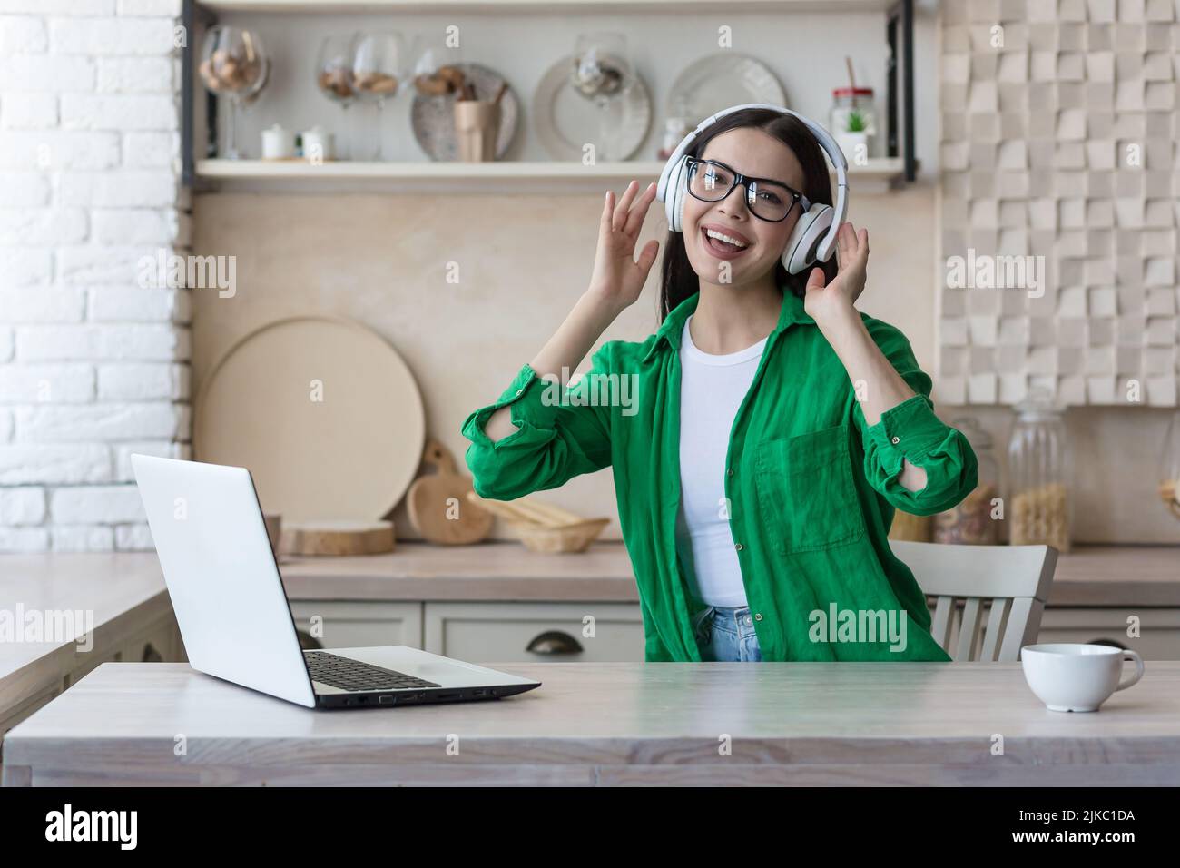 Jolie jeune femme travaillant avec un ordinateur portable et d'écouter la musique à la maison Banque D'Images