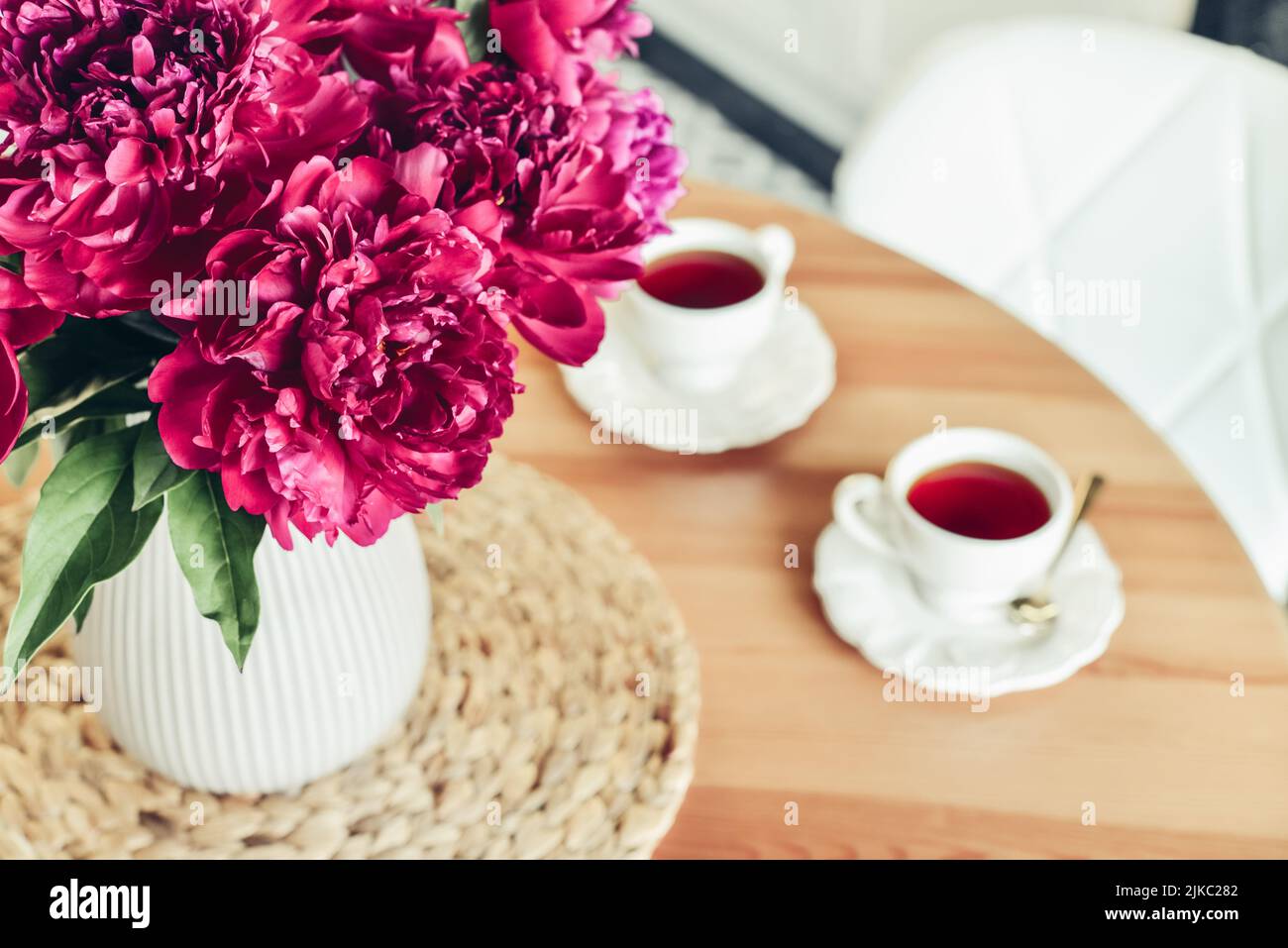 Bouquet de fleurs de pivoines violettes et une tasse de thé à l'intérieur de la cuisine Banque D'Images