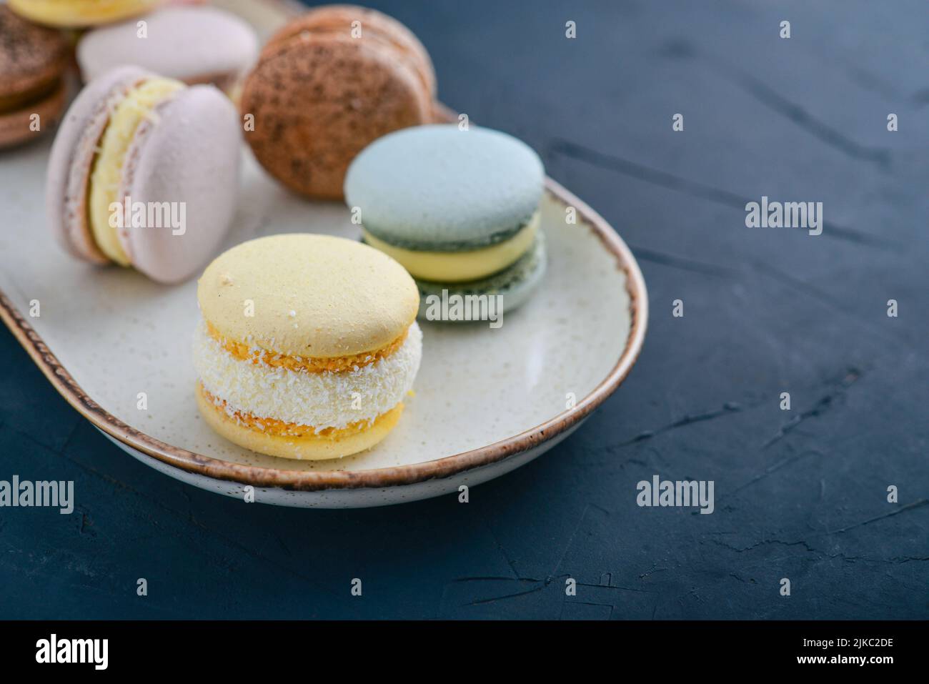 Macarons français colorés sur plaque sur fond noir Banque D'Images