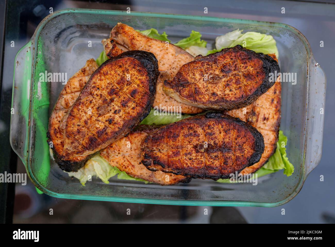 Mise au point sélective. Poisson grillé, steak de saumon grillé avec épices et légumes sur la plaque du gril à l'extérieur, vue de dessus, gros plan. Fruits de mer grillés Banque D'Images