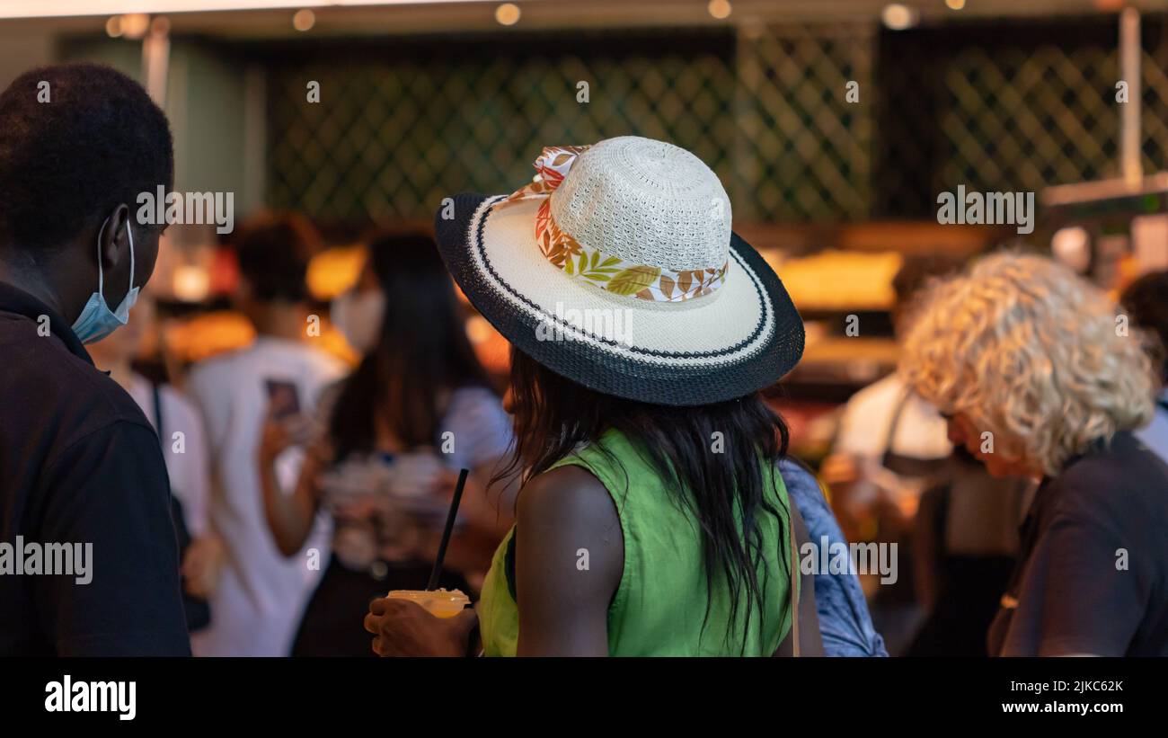 Barcelone, Espagne - 29 juin 2022: Fille avec chapeau blanc de retour dans le marché de Boqueria à Barcelone (Espagne), l'accent sélectif sur le chapeau. Banque D'Images