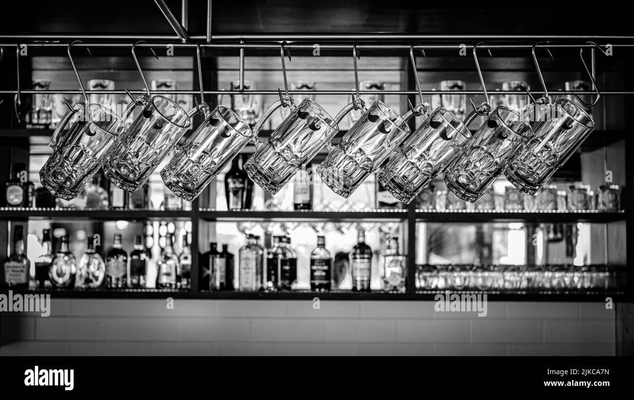 Un verre noir et blanc de tasses à bière accrochées dans un bar Banque D'Images