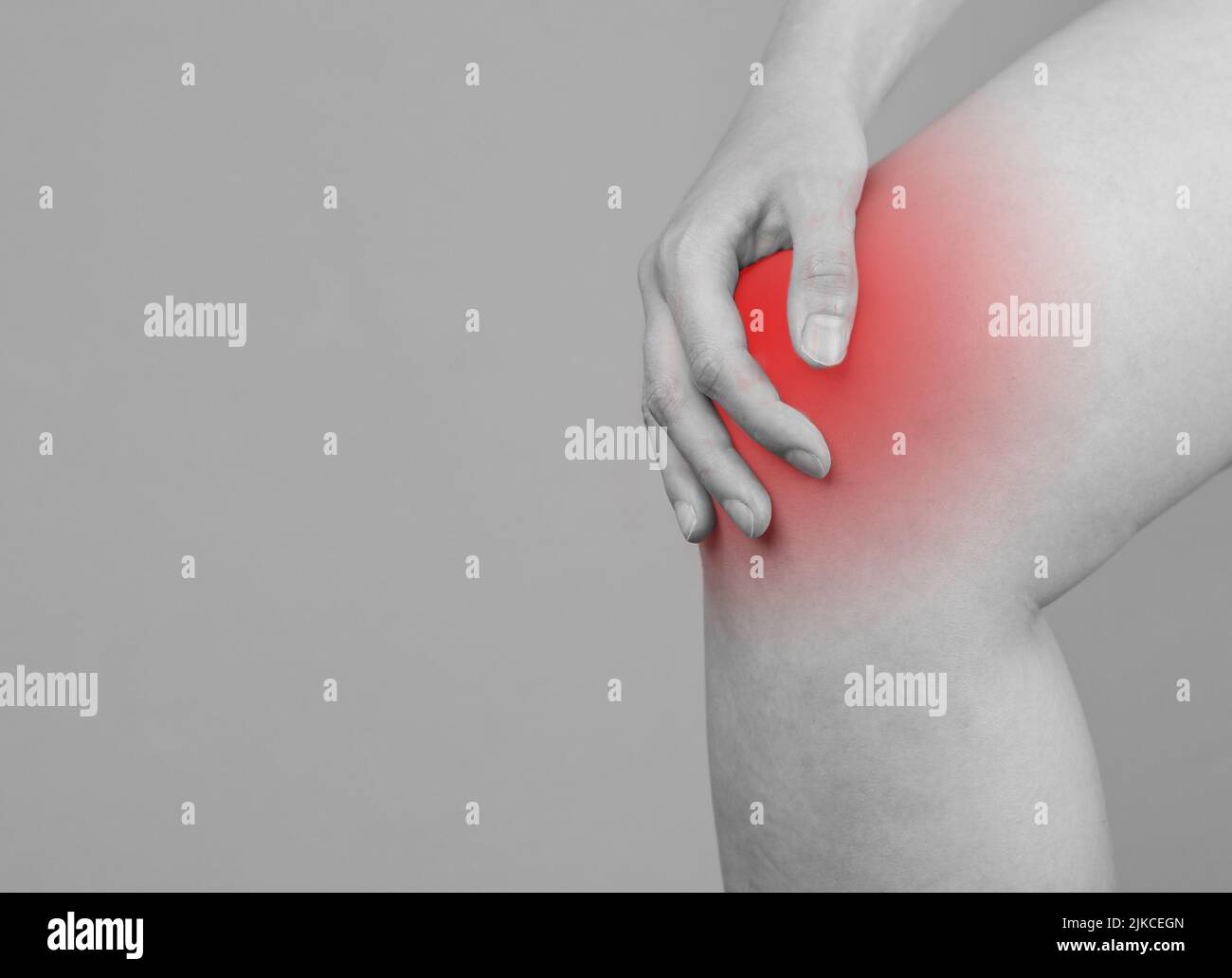 Bannière avec une femme tenant un genou douloureux avec une tache rouge. Douleurs articulaires. Ligaments tentainés, rompus, déchirure du ménisque, tendinite, arthrite. Noir et blanc. Copier l'espace. Photo de haute qualité Banque D'Images