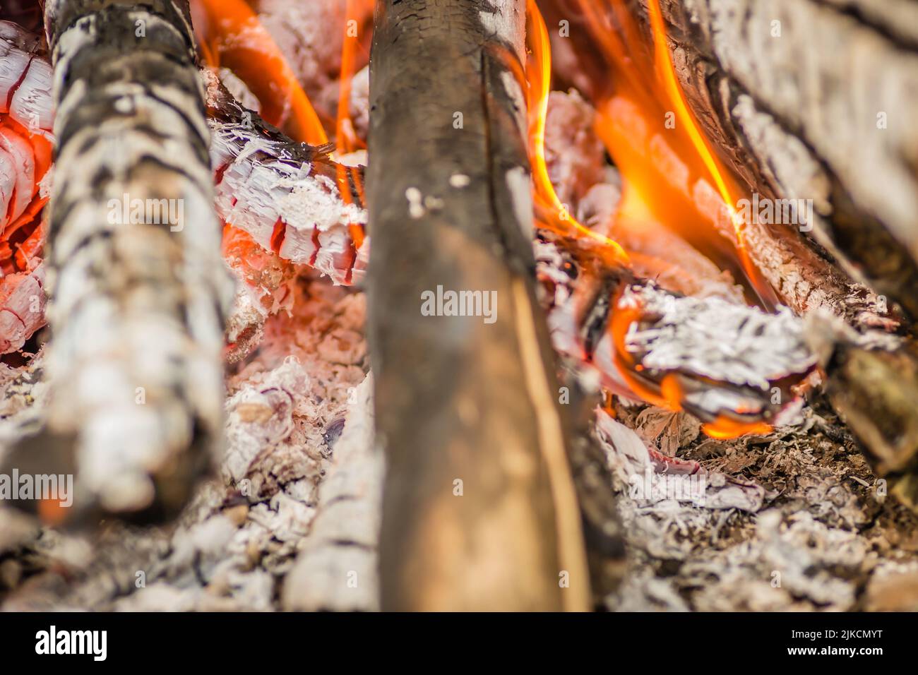 Un gros plan de pièces de bois, de charbon de bois et de cendres qui brûlent dans les flammes Banque D'Images