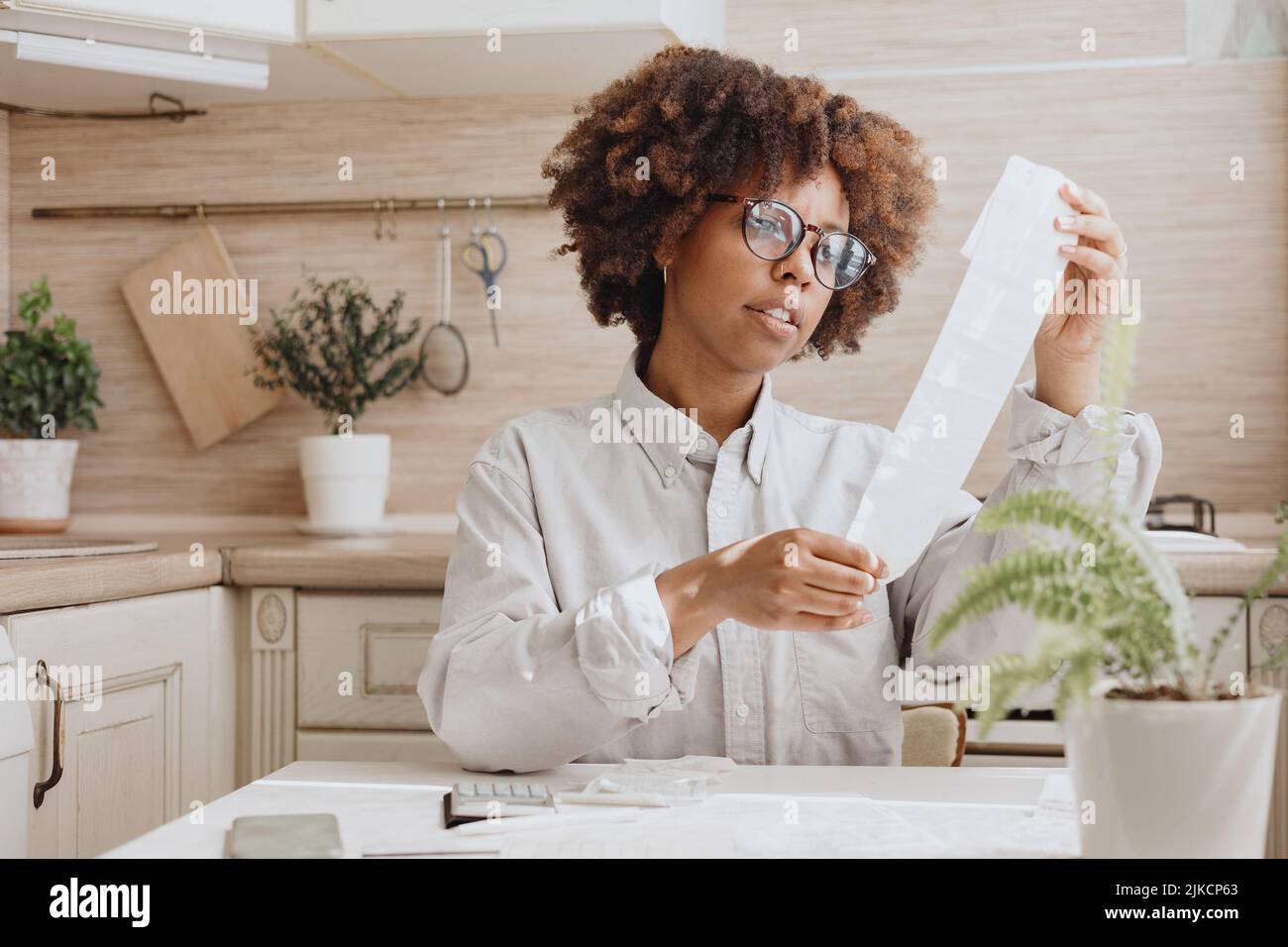 Une femme vérifie les nouveaux prix pour le paiement dans la cuisine. Banque D'Images