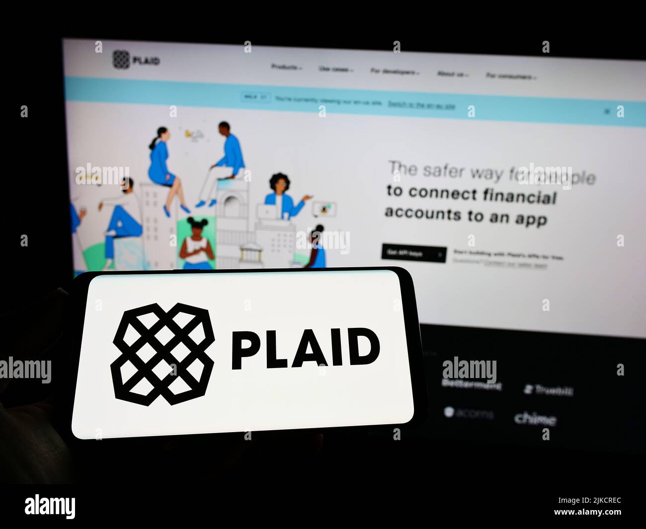 Personne tenant un téléphone mobile avec le logo de la société américaine de Fintech Plaid Inc. À l'écran en face de la page Web d'affaires. Mise au point sur l'affichage du téléphone. Banque D'Images