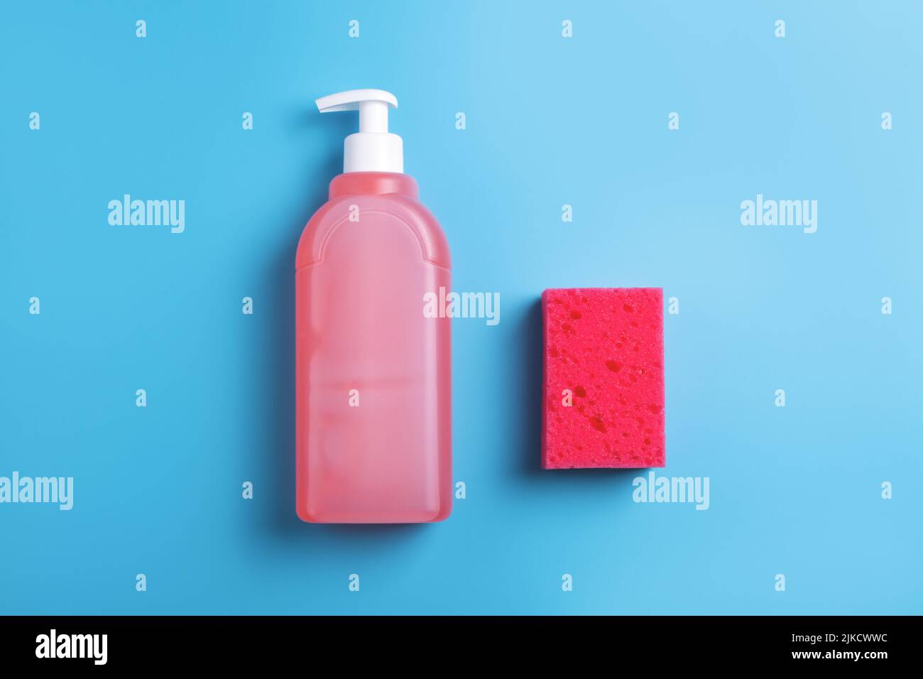 Savon et éponge rouge pour lave-vaisselle sur fond bleu. Vue de dessus. Banque D'Images