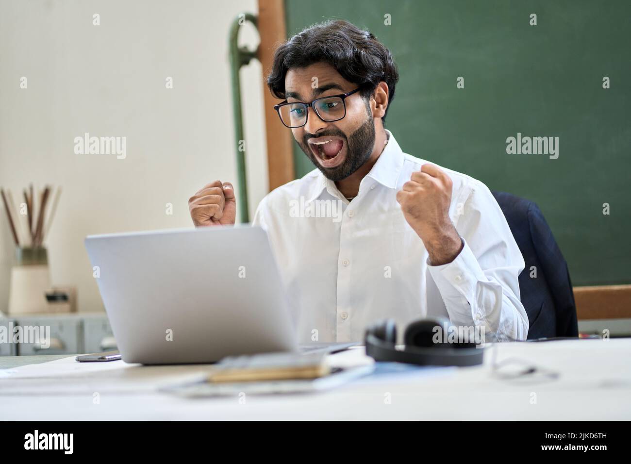 Un homme d'affaires indien enthousiaste regardant un ordinateur portable célébrant la victoire avec oui geste. Banque D'Images