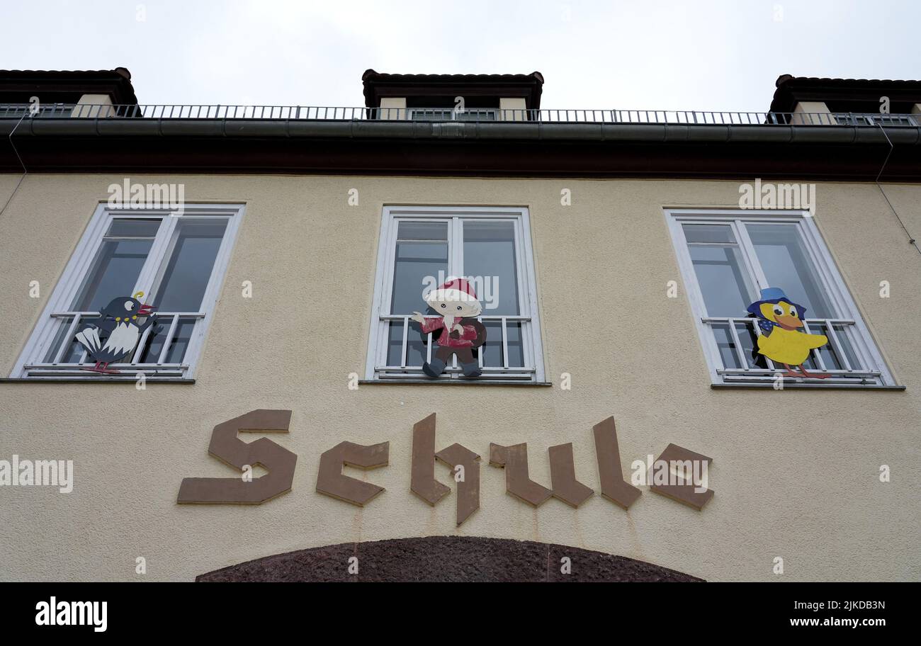 01 août 2022, Brandebourg, Schorfheide/OT Groß Schönebeck: Le mot 'chool' est écrit sur un bâtiment d'école sous des fenêtres ornées des personnages de télévision Mme Elster, Sandman et Schnatterinchen. Photo: Soeren Stache/dpa Banque D'Images