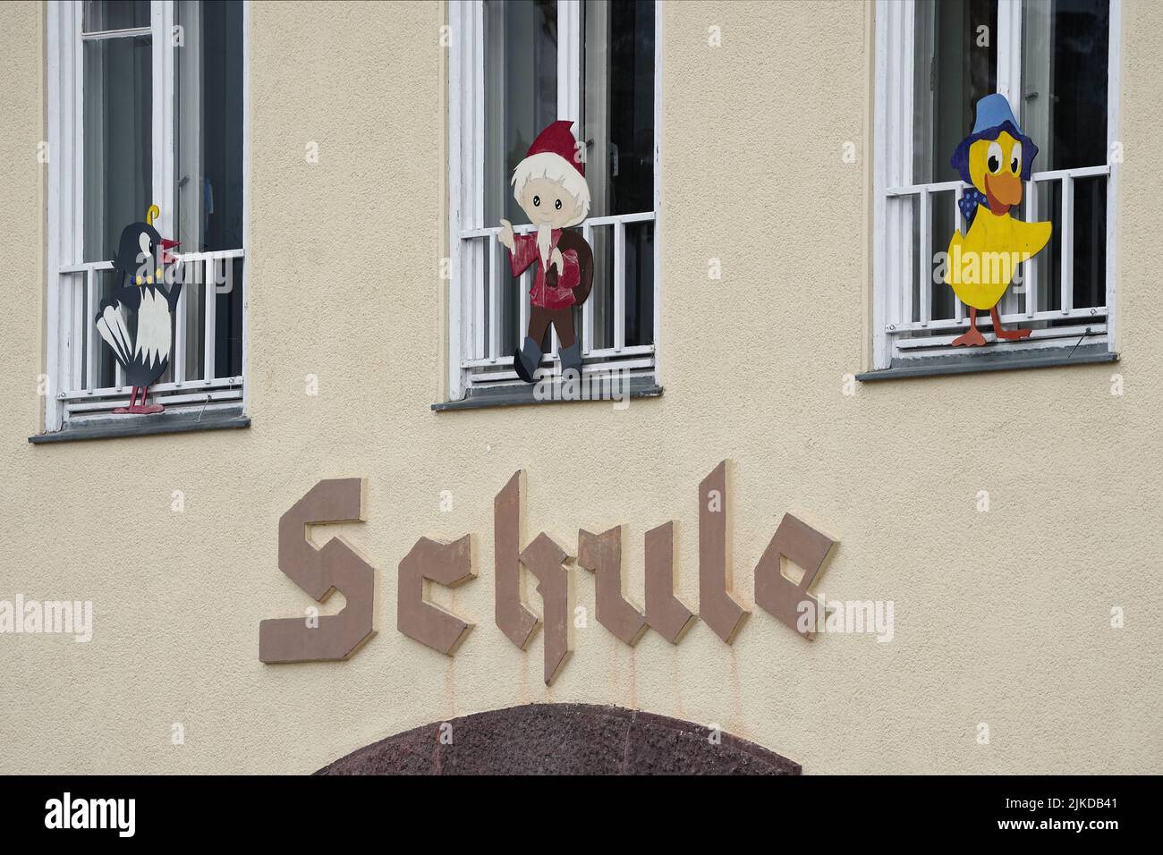 01 août 2022, Brandebourg, Schorfheide/OT Groß Schönebeck: Le mot 'chool' est écrit sur un bâtiment d'école sous des fenêtres ornées des personnages de télévision Mme Elster, Sandman et Schnatterinchen. Photo: Soeren Stache/dpa Banque D'Images