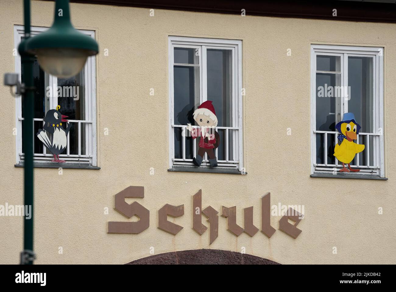 01 août 2022, Brandebourg, Schorfheide/OT Groß Schönebeck: Le mot 'chool' est écrit sur un bâtiment d'école sous des fenêtres ornées des personnages de télévision Mme Elster, Sandman et Schnatterinchen. Photo: Soeren Stache/dpa Banque D'Images
