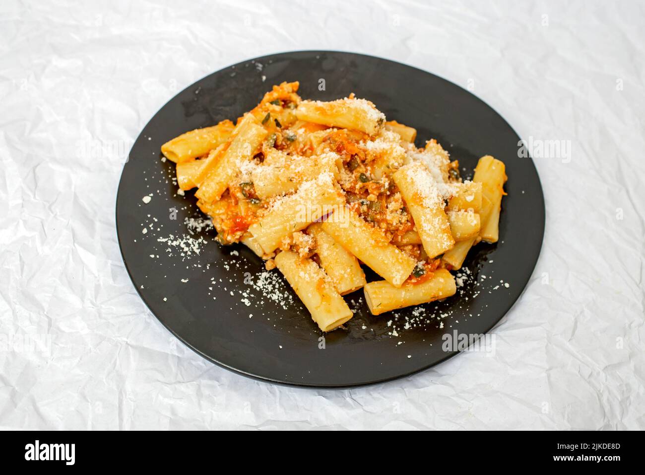 Pâtes bolognaise avec sauce ragu et parmesan sur une assiette noire isolée sur blanc Banque D'Images