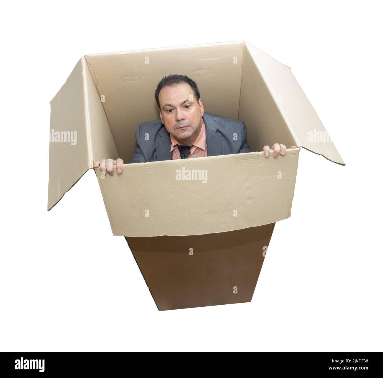 Un homme en costume se tient à l'intérieur d'une boîte en carton et essaie de regarder dehors, isolé sur fond blanc Banque D'Images