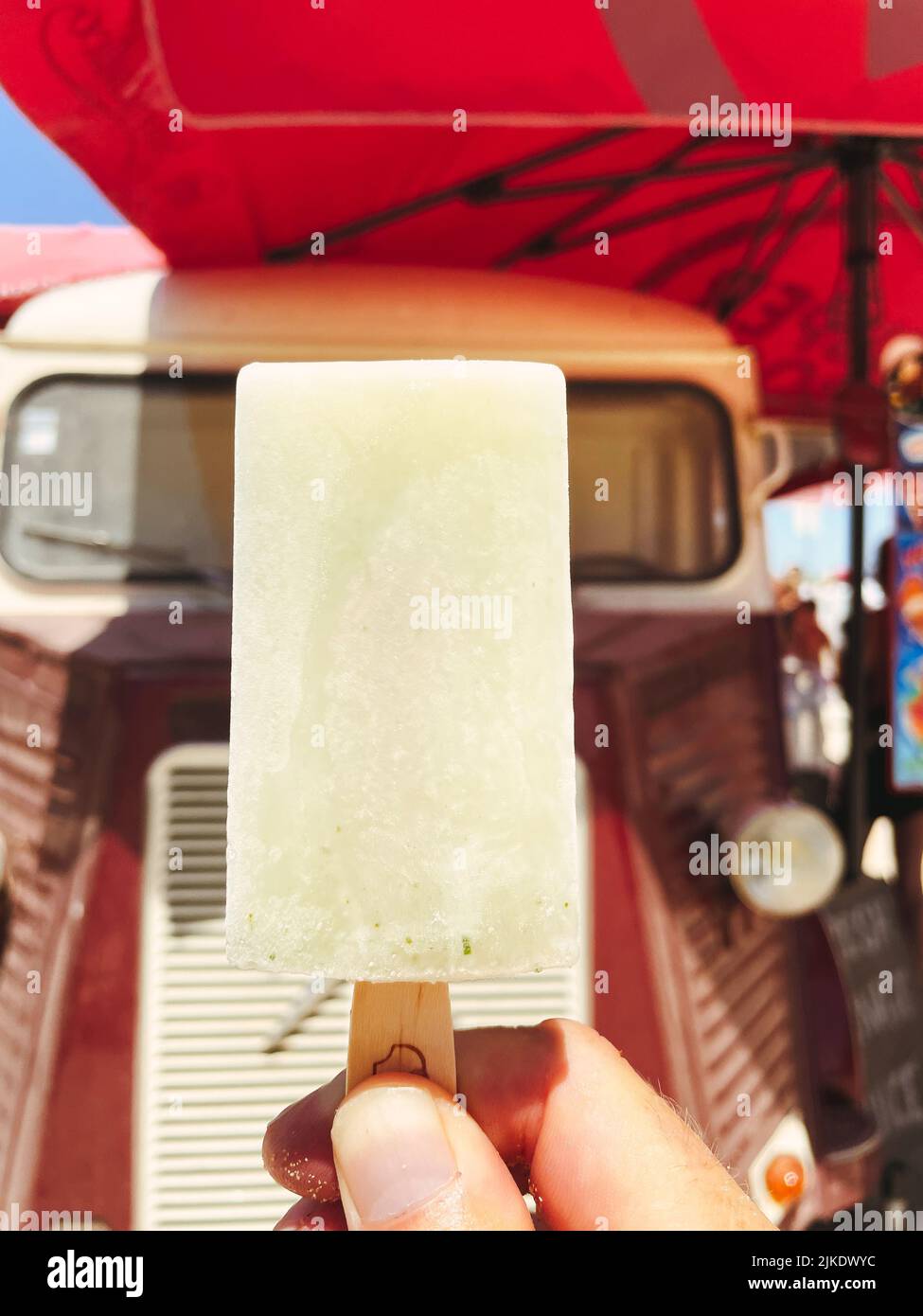 Main tenant une glace avec un camion de glace vintage en arrière-plan. Banque D'Images