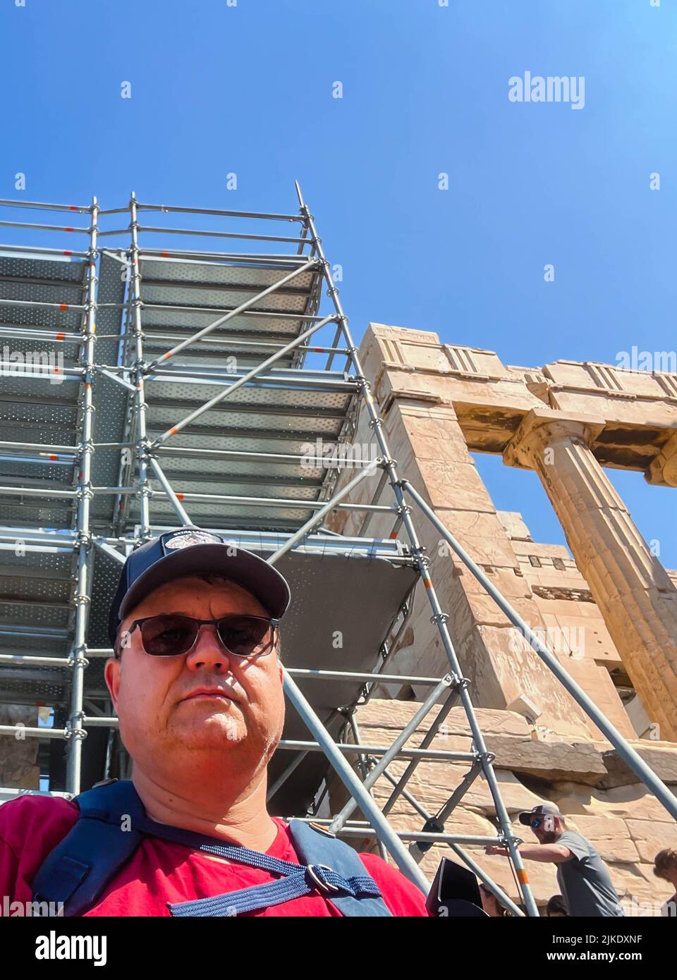 ATHÈNES, GRÈCE - 14 MAI 2022 : un homme en casquette de baseball et un t-shirt rouge est photographié devant l'Acropole d'Athènes, Grèce. Jour ensoleillé. Banque D'Images