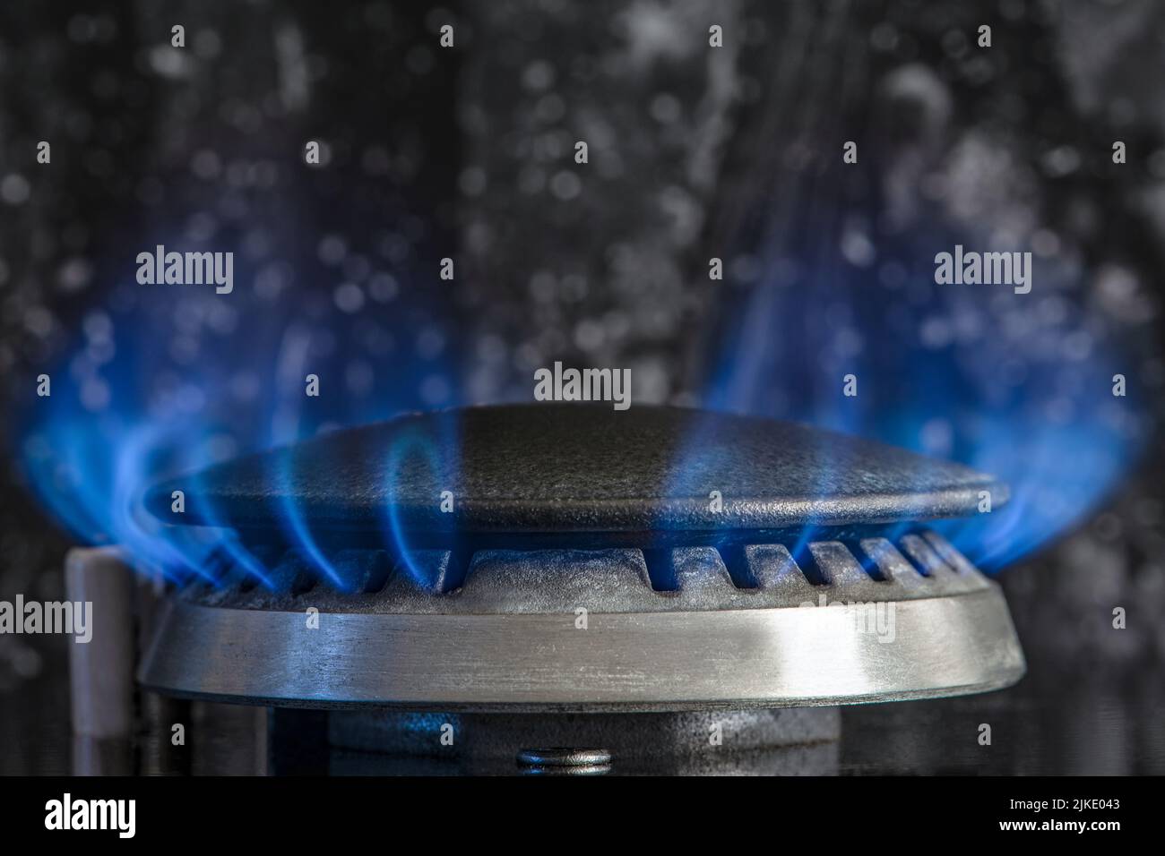 Combustion de gaz naturel, propane. Cuisinière à gaz sur fond noir. Fragment d'une cuisinière à gaz avec une flamme bleue, gros plan. Crise énergétique Banque D'Images