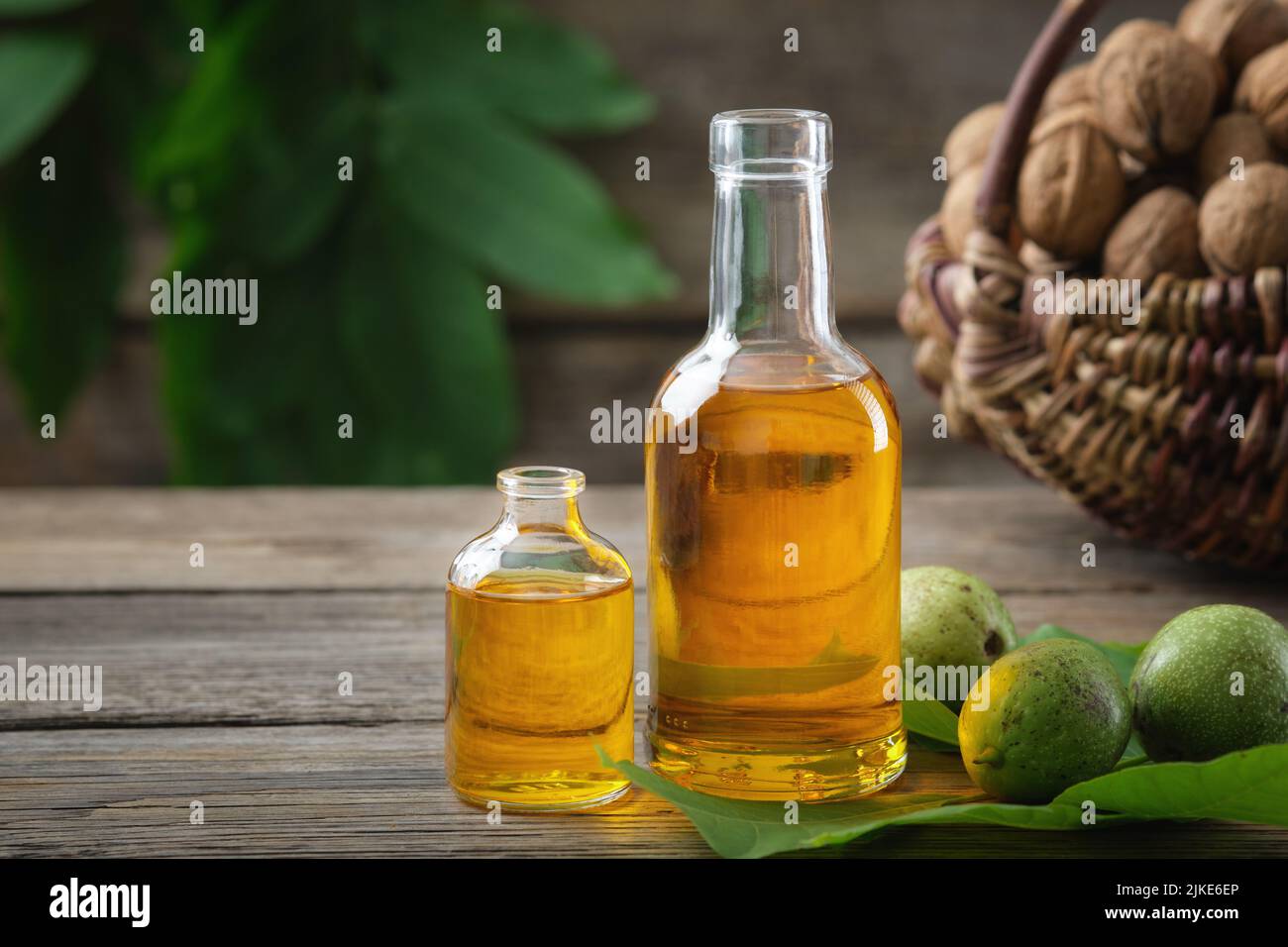 Bouteilles d'huile de noix essentielle, noix vertes et mûres. Panier de noix sur fond. Banque D'Images