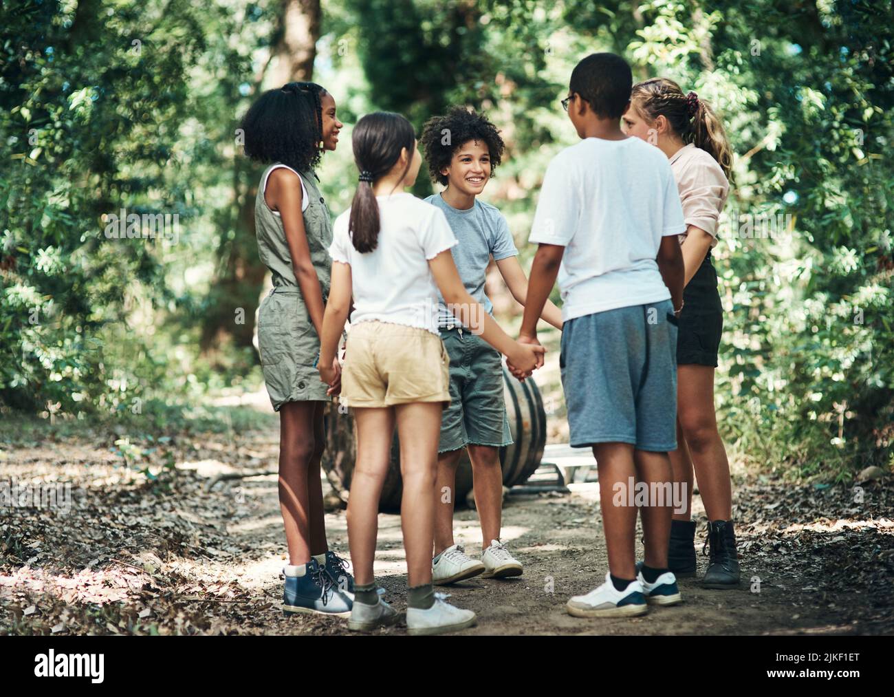 Un superbe camp pour les enfants. Un groupe d'adolescents debout dans un cercle et tenant les mains dans la nature au camp d'été. Banque D'Images