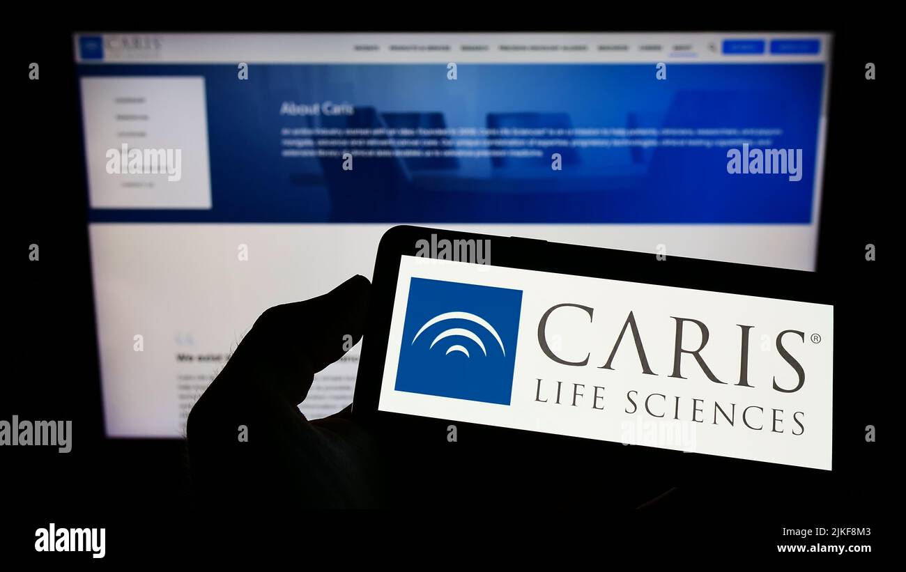 Personne tenant un smartphone avec le logo de la société américaine de biotechnologie CARIS Life Sciences à l'écran devant le site Web. Mise au point sur l'affichage du téléphone. Banque D'Images