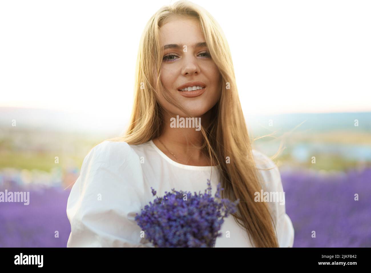 Gros plan portrait d'une jeune femme tenant un bouquet de lavande blaniile debout dans le champ de lavande Banque D'Images