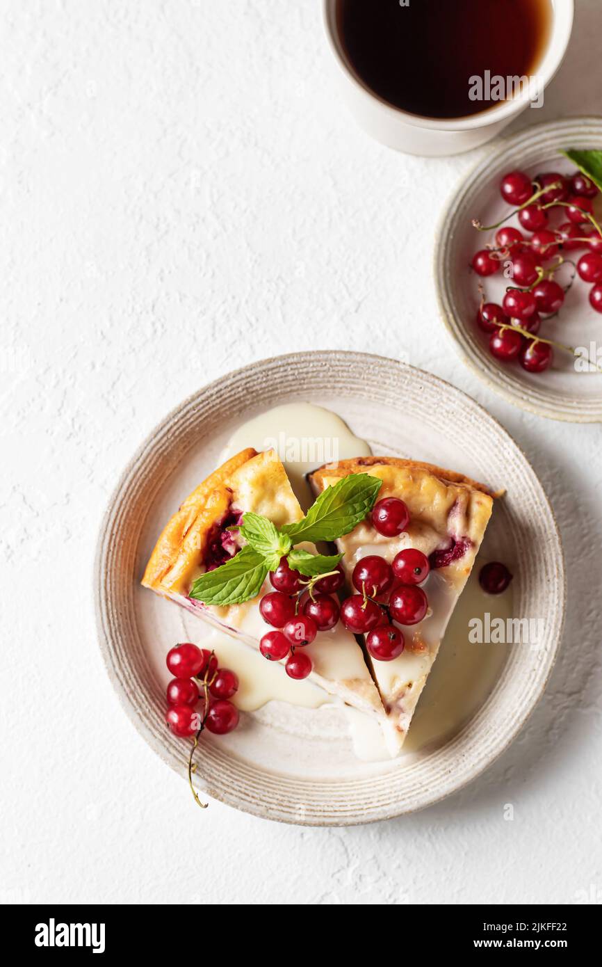 Cocotte de fromage cottage avec baies fraîches d'été et tasse de thé sur table blanche pour un petit déjeuner sain. Vue de dessus, espace de texte, pose à plat Banque D'Images