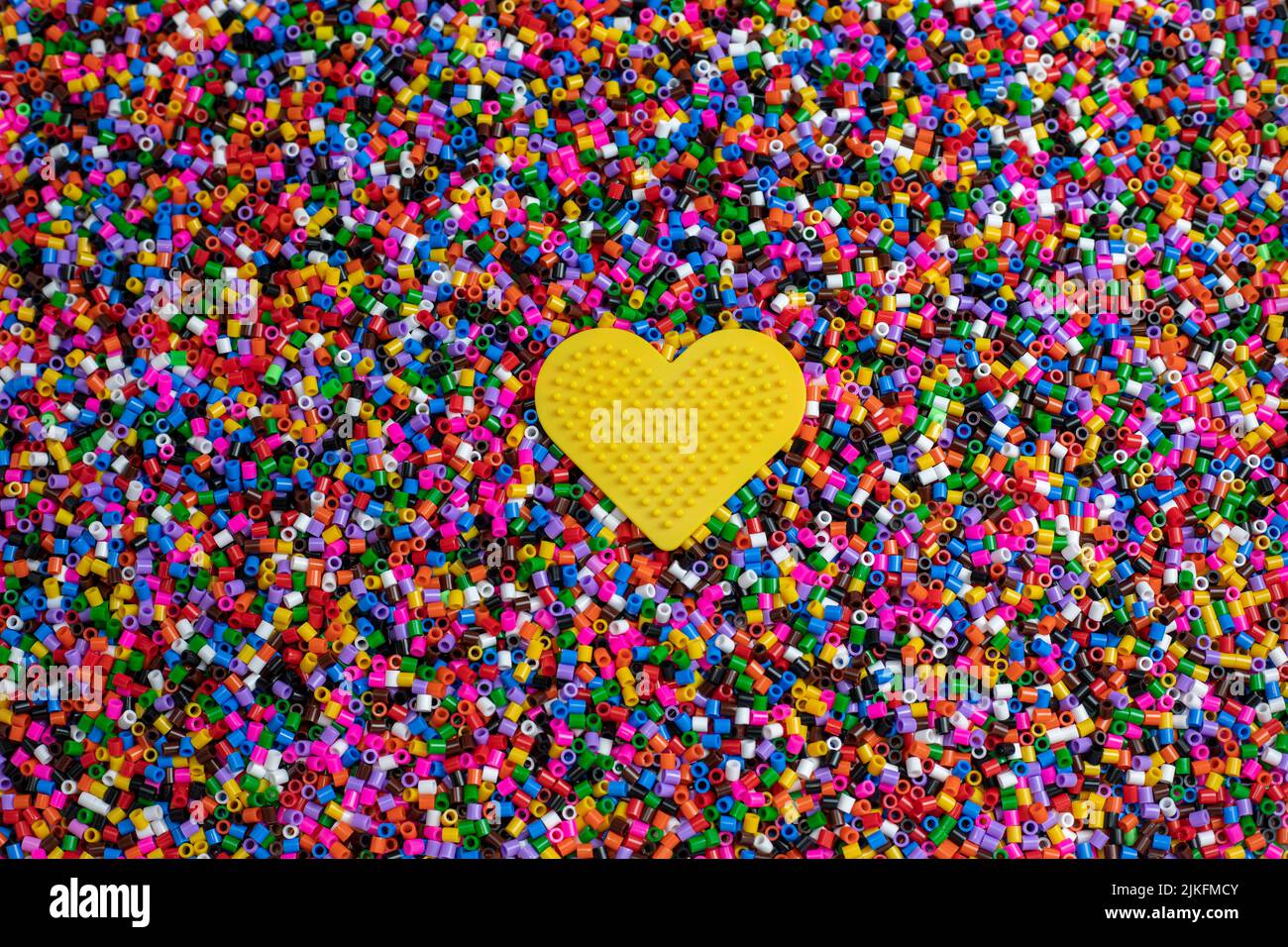 Ensemble de pièces en plastique cylindriques multicolores à encornir sur un coeur jaune et former des formes géométriques Banque D'Images