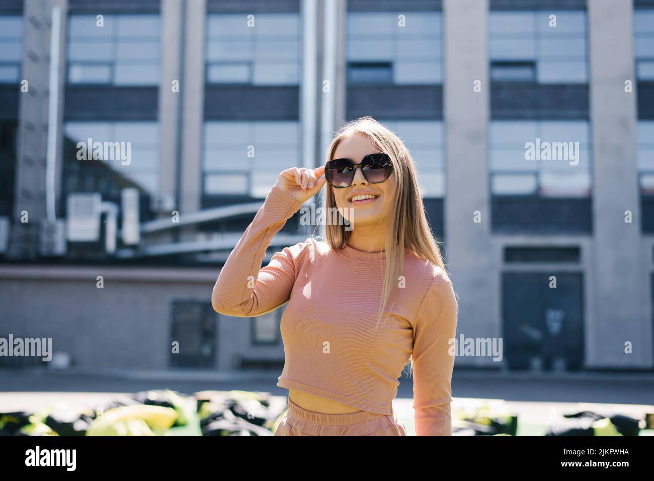 Portrait d'une femme souriante heureuse portant des lunettes de soleil en ville en été Banque D'Images