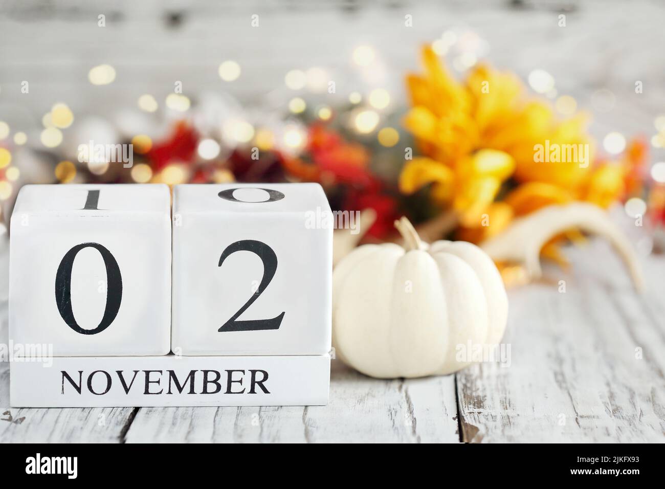 Blocs de calendrier en bois blanc avec la date 2 novembre et les décorations d'automne sur une table en bois. Mise au point sélective avec arrière-plan flou. Banque D'Images