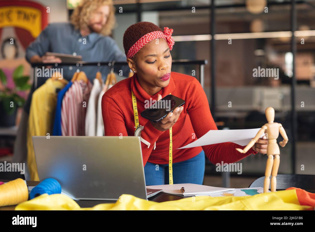 Une jeune femme de mode afro-américaine prend commande par téléphone intelligent dans un bureau de studio Banque D'Images