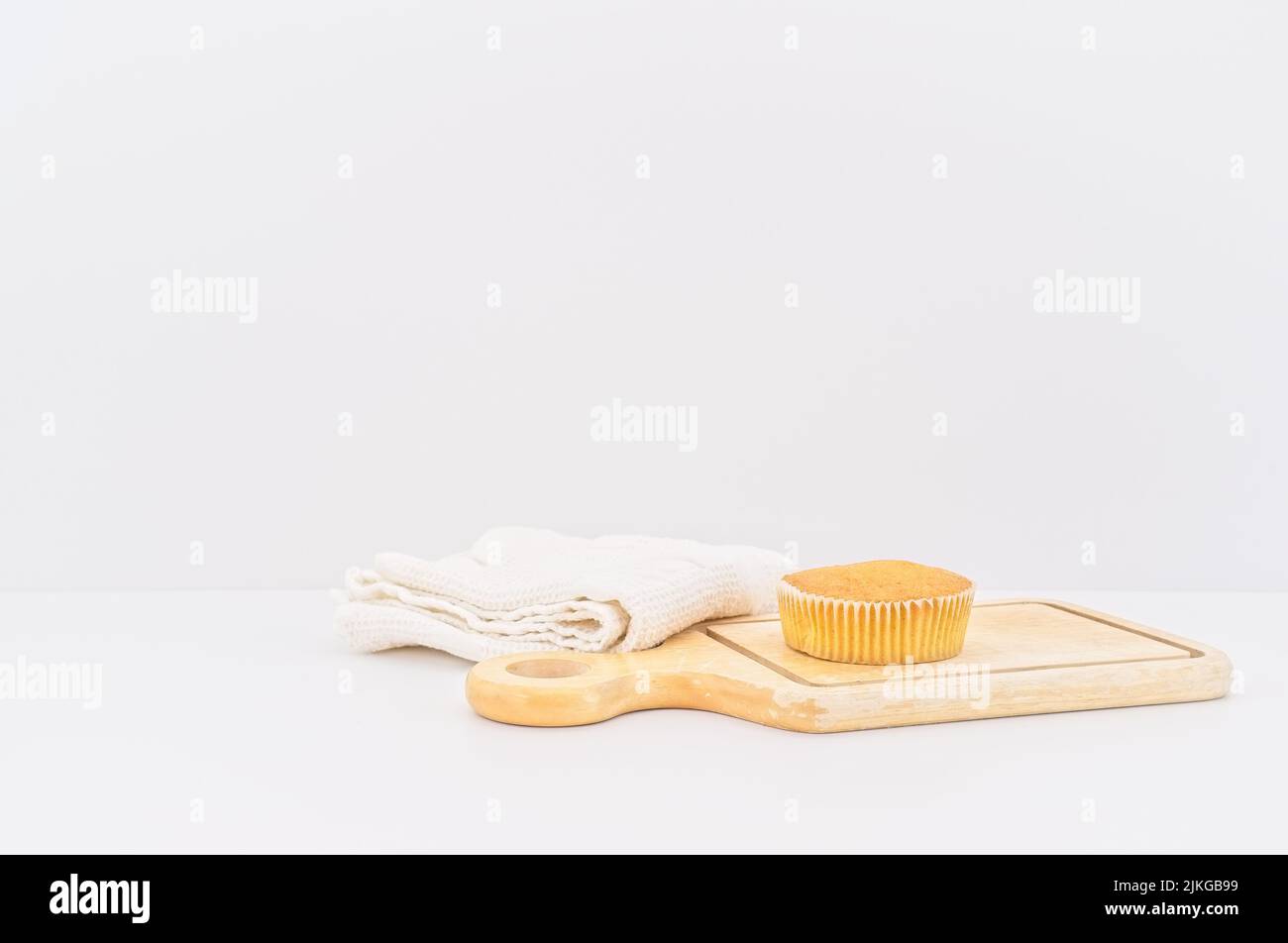 gâteau de carottes bio dans une tasse en papier avec farine d'épeautre, serviette de cuisine et planche à découper en bois sur une table blanche Banque D'Images