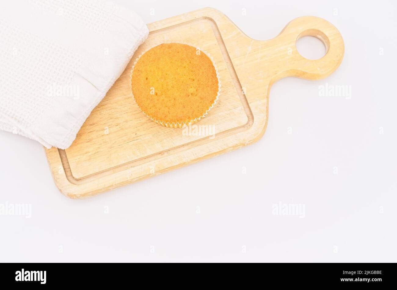 gâteau de carottes bio dans une tasse en papier avec farine d'épeautre, serviette de cuisine et planche à découper en bois sur une table blanche Banque D'Images