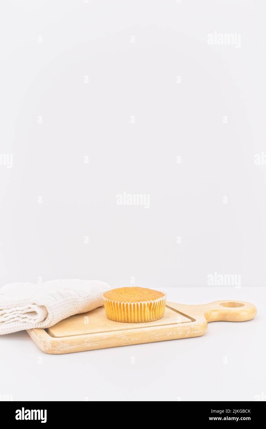 gâteau de carottes bio dans une tasse en papier avec farine d'épeautre, serviette de cuisine et planche à découper en bois sur une table blanche Banque D'Images