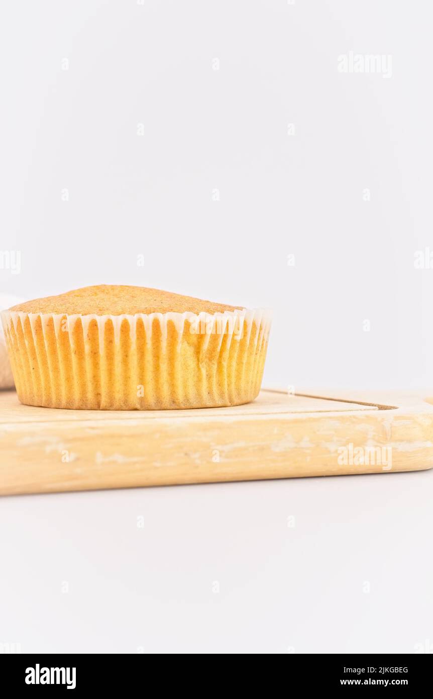 gâteau de carottes bio dans une tasse en papier avec farine d'épeautre, serviette de cuisine et planche à découper en bois sur une table blanche Banque D'Images