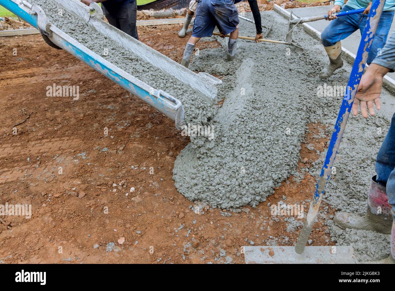 Aider à verser du ciment sur une nouvelle allée en béton pour un immeuble d'appartements Banque D'Images