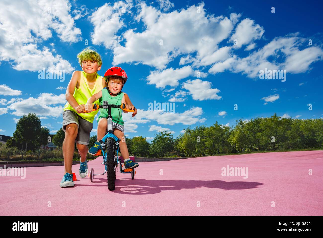 Portrait grand garçon pousser petit vélo enseigner à monter un vélo Banque D'Images