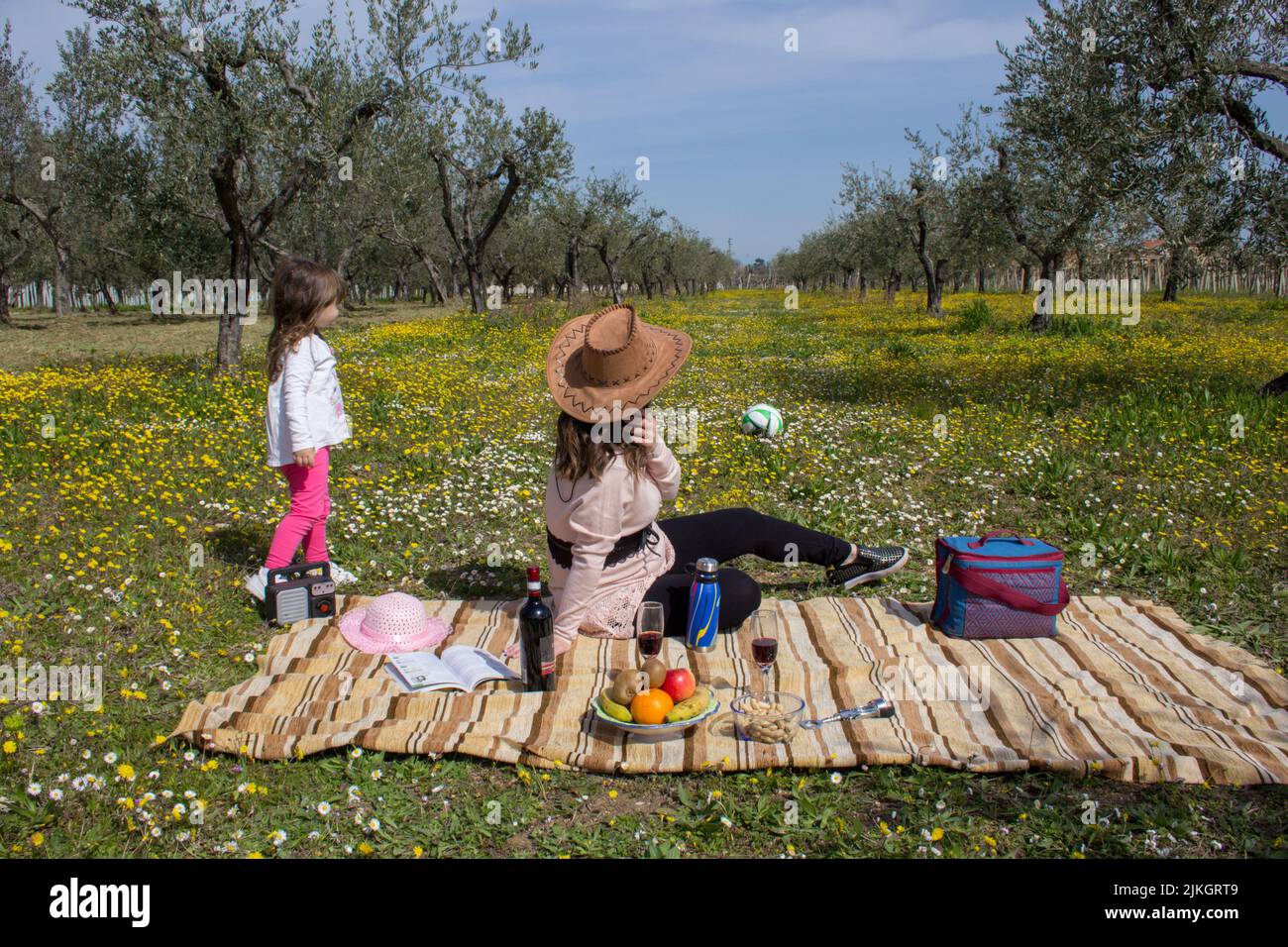 Image d'une mère portant un chapeau de cow-boy avec sa fille dans un champ à la campagne pendant qu'ils jouent sur un pique-nique. Vacances en Toscane Italie Banque D'Images