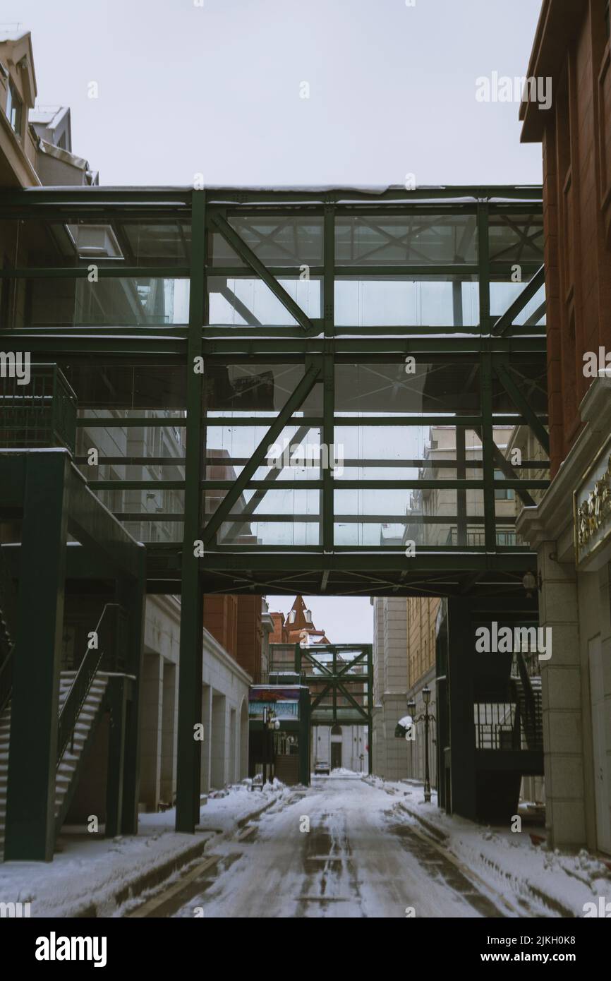Un couloir de verre entre les bâtiments au-dessus d'une route enneigée Banque D'Images