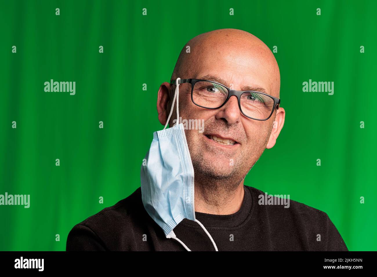portrait bald man avec lunettes et fond vert avec masque covid Banque D'Images